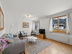 A living room with a sofa, chairs, a TV, a table, and a large window with a view of mountains. - Bellavista 4 Appartement/Fewo, Bad, WC, 2 Schlafräume Ferienwohnung Bellavista 4 by Interhome (Parpan)