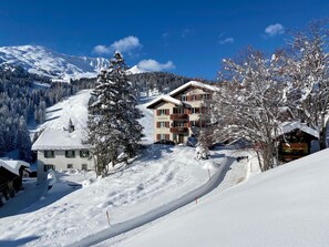 A snow-covered mountain resort with a multi-story building, ski slopes, and a clear blue sky. - Bellavista 4 Appartement/Fewo, Bad, WC, 2 Schlafräume Ferienwohnung Bellavista 4 by Interhome (Parpan)