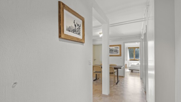 A hallway with a framed picture on the wall, a dining area with a table and chairs, and a bedroom with a bed and window. - Bellavista 4 Appartement/Fewo, Bad, WC, 2 Schlafräume Ferienwohnung Bellavista 4 by Interhome (Parpan)