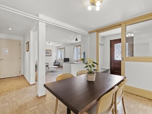 A dining area with a wooden table and chairs, a potted plant, and a view of a kitchen and living space. - Bellavista 4 Appartement/Fewo, Bad, WC, 2 Schlafräume Ferienwohnung Bellavista 4 by Interhome (Parpan)