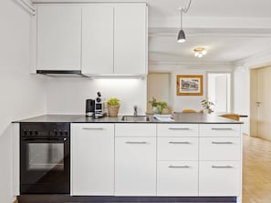 A modern kitchen with white cabinetry, a built-in oven, and a stainless steel sink.