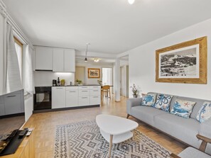 A modern living room with a grey sofa, patterned rug, and a white coffee table.