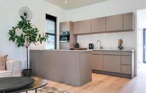 Eine moderne Küche mit einer zentralen Kochinsel, integrierten Geräten und einem Essbereich mit Sofa und Couchtisch.