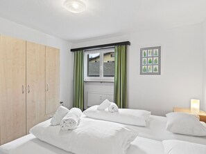 A hotel room with two beds, a wooden wardrobe, a window with curtains, and a wall-mounted picture. - Seeli Appartement/Fewo,   Ferienwohnung Seeli by Interhome (Churwalden)