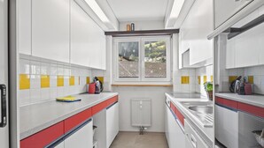 Eine moderne Küche mit weißen Schränken, einem Fenster mit Aussicht und einer roten und weißen Arbeitsplatte.