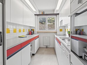 A modern kitchen with white cabinets, a window with a view, and a red and white countertop. - Seeli Appartement/Fewo,   Ferienwohnung Seeli by Interhome (Churwalden)