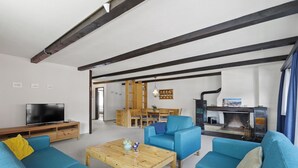 Ein Wohnzimmer mit blauen Sofas, einem Holztisch und einem Fernseher.