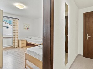 Ein Schlafzimmer mit einem Bett, einem Nachttisch, einem Fenster mit Vorhängen und einer Tür.