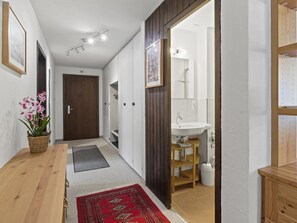 A hallway with a wooden door, a white sink, and a mirror in a bathroom. - Seeli Appartement/Fewo,   Ferienwohnung Seeli by Interhome (Churwalden)