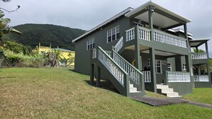 A two-story building with a balcony, a staircase, and a view of a hill. - Peaceful 3BR St. Kitts Mountain Getaway (Saint Peter)