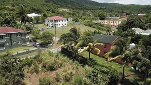 A residential area with houses, a large building with a red roof, and a mountainous backdrop. - Peaceful 3BR St. Kitts Mountain Getaway (Saint Peter)