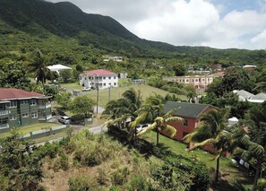 Un barrio residencial con casas, un edificio grande de techo rojo y montañas al fondo.
