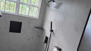 A bathroom with a toilet, a shower, a sink, a towel, and a window. - Peaceful 3BR St. Kitts Mountain Getaway (Saint Peter)