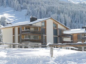 A multi-story building with balconies, surrounded by snow-covered trees and a ski slope in the background. - Triangel Raber Appartement/Fewo Triangel Raber by Interhome (Parpan)