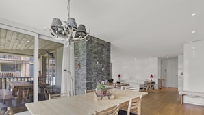 A modern dining area with a wooden table and chairs, a stone accent wall, and a glass door leading to an outdoor space. - Triangel Raber Appartement/Fewo Triangel Raber by Interhome (Parpan)