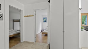 Ein modernes Schlafzimmer mit Etagenbett, Kleiderschrank und kleinem Bad.