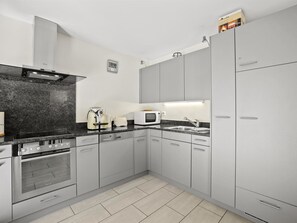 A modern kitchen with grey cabinets, a built-in oven, a microwave, and a coffee maker. - Hemmadi Appartement/Fewo,   Ferienwohnung Hemmadi by Interhome (Churwalden)