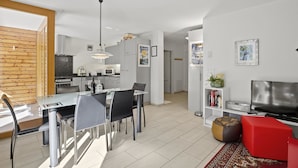 Eine moderne Wohnung mit Essbereich, Küche, Wohnzimmer und Fernseher.