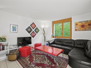 A living room with a red coffee table, black leather sofa, and a TV on a white stand. - Hemmadi Appartement/Fewo,   Ferienwohnung Hemmadi by Interhome (Churwalden)