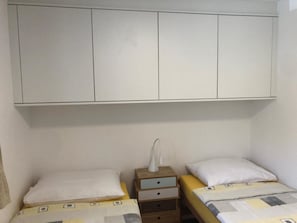 A bedroom with two single beds, a nightstand with a lamp, and a wardrobe with a mirror. - Haus Allod 201 Appartement/Fewo Allod 201 Gretler by Interhome (Lenzerheide)