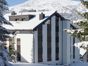 A modern building with a sloped roof, large windows, and a snow-covered landscape. - Al Prada 3.1.a Appartement/Fewo,   Ferienwohnung Al Prada 3.1.a by Interhome (Lenzerheide)