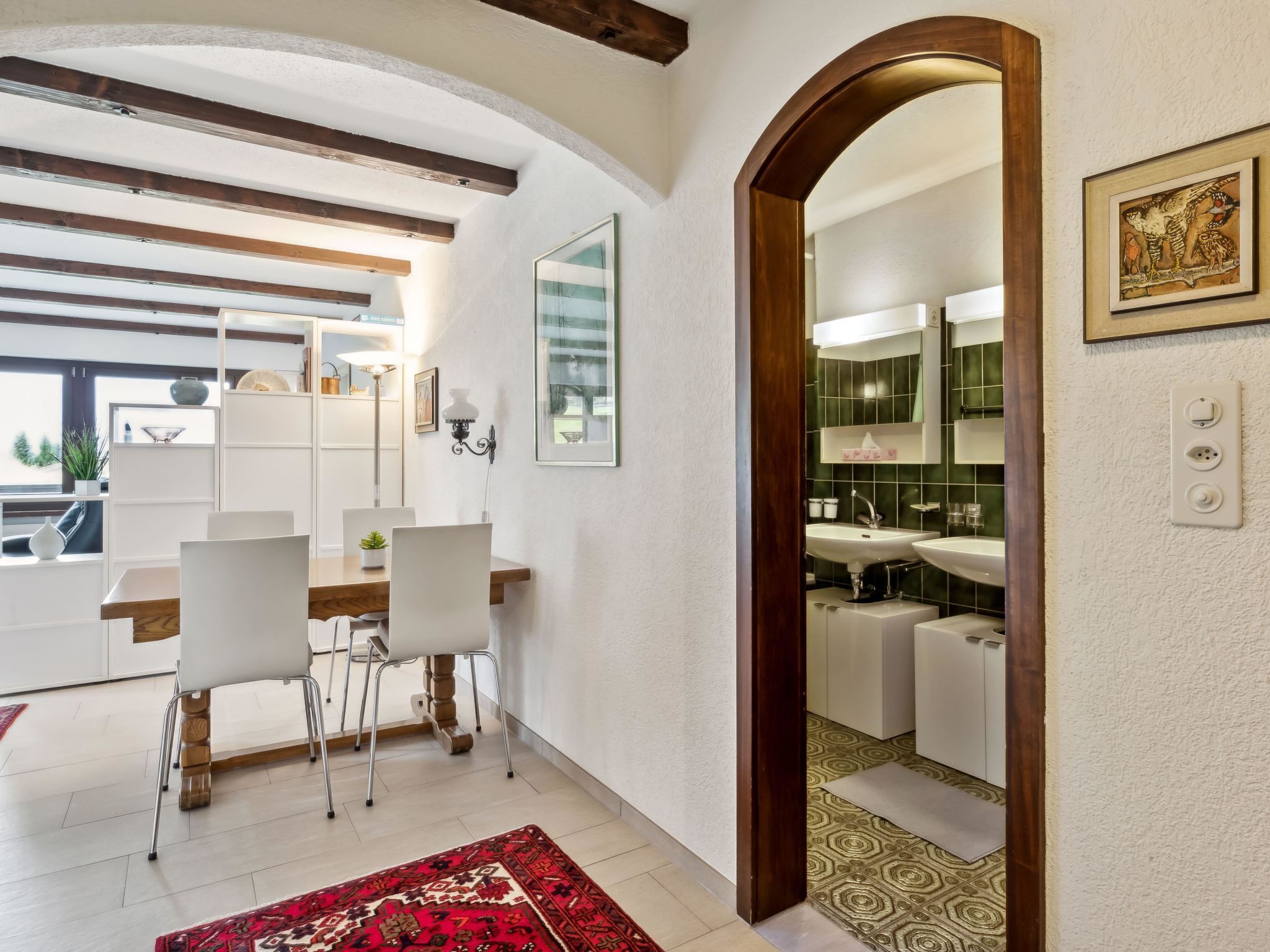 Een modern interieur met een eethoek, keuken en een grote spiegel die de ruimte weerspiegelt.