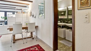 Ein modernes Interieur mit Essbereich, Küche und einem großen Spiegel, der den Raum reflektiert.