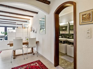 Un interior moderno con comedor, cocina y un espejo grande que refleja el ambiente.