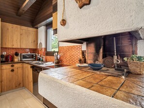Cocina con armarios de madera, microondas, fregadero y encimera de piedra.