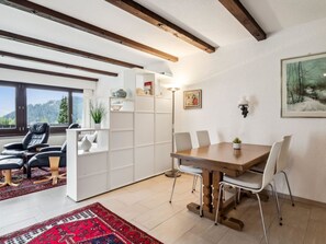 A modern living room with a dining area, featuring a large window, a fireplace, and a view of the outdoors. - Al Prada 3.1.a Appartement/Fewo,   Ferienwohnung Al Prada 3.1.a by Interhome (Lenzerheide)
