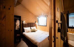 Une pièce aménagée comme une tente, avec un lit, une armoire et une fenêtre.