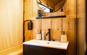 Ein Badezimmer aus Holz mit Waschbecken, Spiegel und Pflegeprodukten.