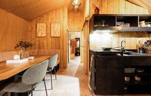 Ein Holzinnenraum mit Essbereich, Küche und einem Flur, der zum Schlafzimmer führt.