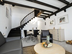 A modern living room with a curved staircase, a dining area, and a kitchen area. - La Schmetta 11 Appartement/Fewo 5 Bettwohnung IH/ED by Interhome (Lenzerheide)