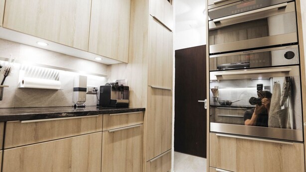 A modern kitchen with wooden cabinets, a coffee machine, and a built-in oven. - La Schmetta 11 Appartement/Fewo 5 Bettwohnung IH/ED by Interhome (Lenzerheide)