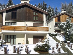 A two-story wooden house with a balcony, surrounded by snow-covered trees. - La Schmetta 11 Appartement/Fewo 5 Bettwohnung IH/ED by Interhome (Lenzerheide)