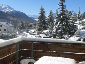 A wooden deck with a bench, overlooking a snowy landscape with houses and mountains. - La Schmetta 11 Appartement/Fewo 5 Bettwohnung IH/ED by Interhome (Lenzerheide)