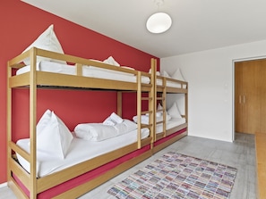 Ein Schlafraum mit Etagenbetten, einer roten Wand und einer Holztür.