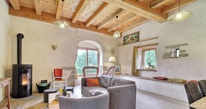 A cozy living room with a fireplace, wooden ceiling beams, and comfortable seating. - The owl shelter (LANGONNET)