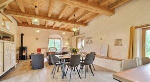 A dining area with a wooden ceiling, a fireplace, and a view of the outdoors. - The owl shelter (LANGONNET)
