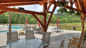 Ein überdachter Außenbereich mit Pool, Liegestühlen und Tischen.