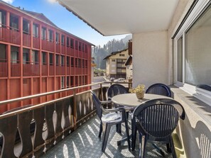 A balcony with a table and chairs, a red building, and a mountain view. - Lang Appartement/Fewo,   Ferienwohnung Lang by Interhome (Churwalden)