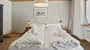 A neatly made bed with white linens, two bedside lamps, a framed picture on the wall, and a wooden ceiling. - Riedblick Appartement/Fewo,   Ferienwohnung Riedblick by Interhome (Churwalden)