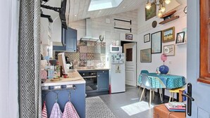 A compact kitchen with a microwave, oven, and sink. There is a dining area with a table and chairs. - Géraldine - LE PALAIS - Gîte (LE PALAIS)