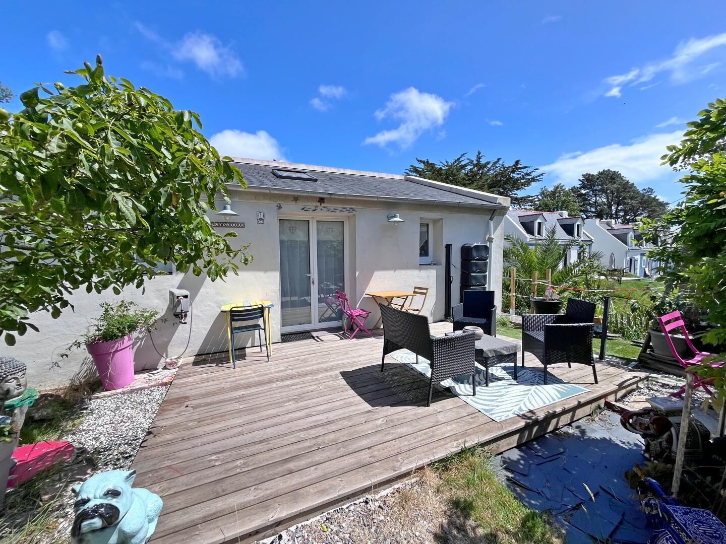 A house with a wooden deck, outdoor seating, and a garden.