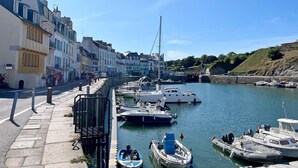 A marina with boats docked, a pedestrian walkway, and buildings along the water. - Géraldine - LE PALAIS - Gîte (LE PALAIS)
