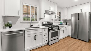 Une cuisine moderne avec des meubles blancs, des appareils en acier inoxydable et un plancher en bois.