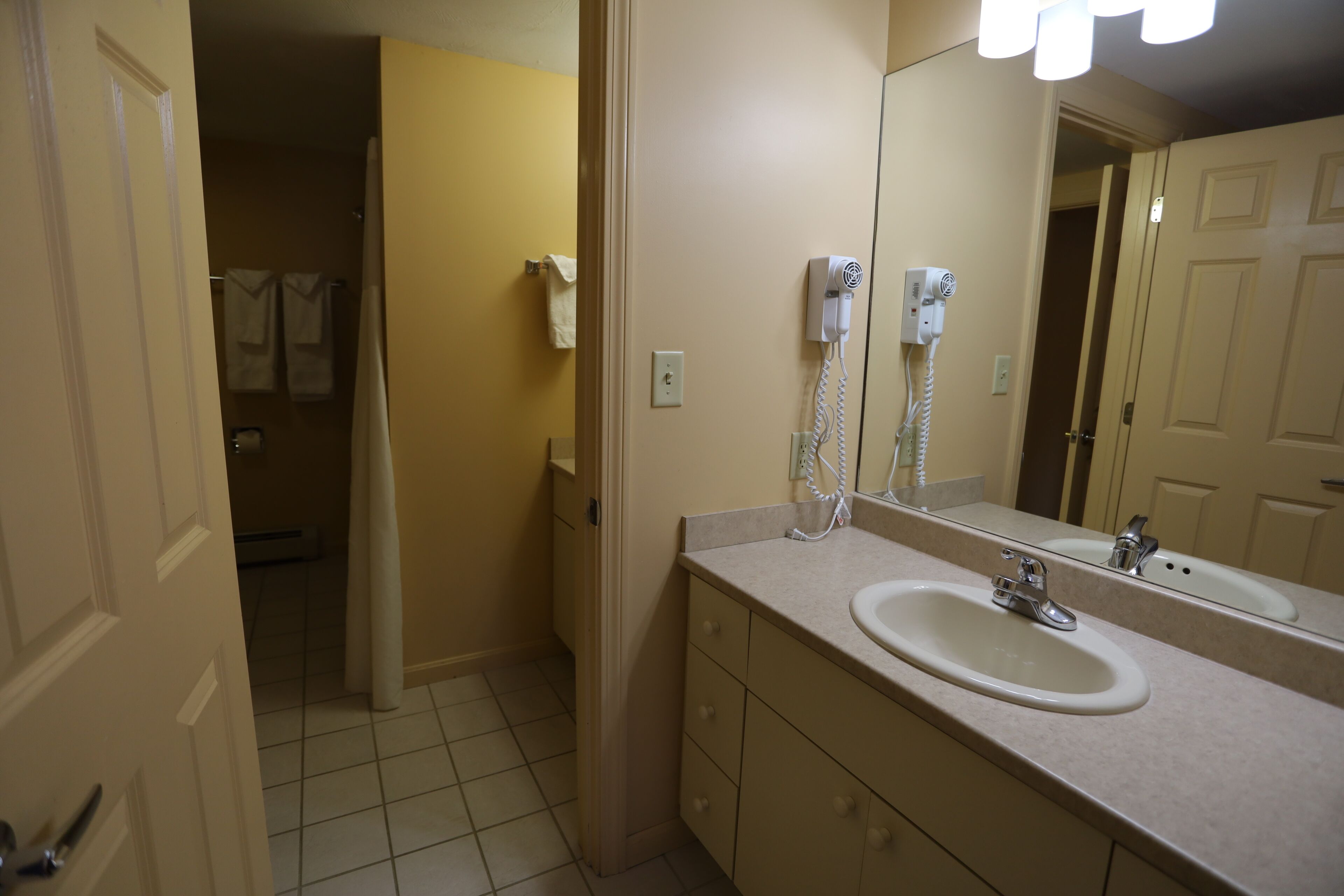 A bathroom with a sink, mirror, and hairdryer.