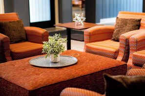 A seating area with orange patterned sofas and a small table with a plant. - Spend July 4th at Pollard Brook in Lincoln! (Lincoln)