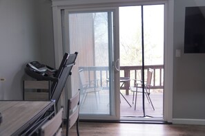Ein Zimmer mit Laufband, einer Glastür zu einer Terrasse mit Stühlen und einem Tisch.